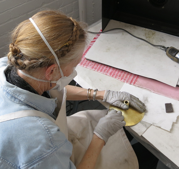 Susan Wood polishing parts of the clock.